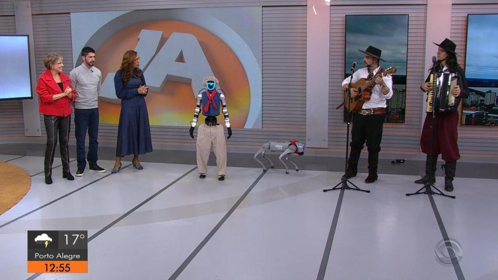 Tenório, robô humanoide de bombacha e lenço, no estúdio do Jornal do Almoço, ao lado de apresentadores, músicos e um cão-robô.